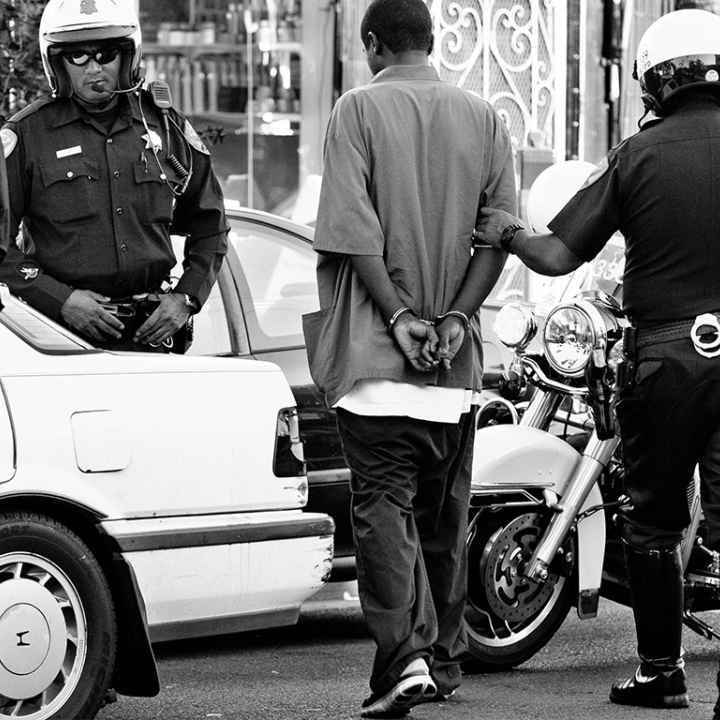 Police surrounding handcuffed man